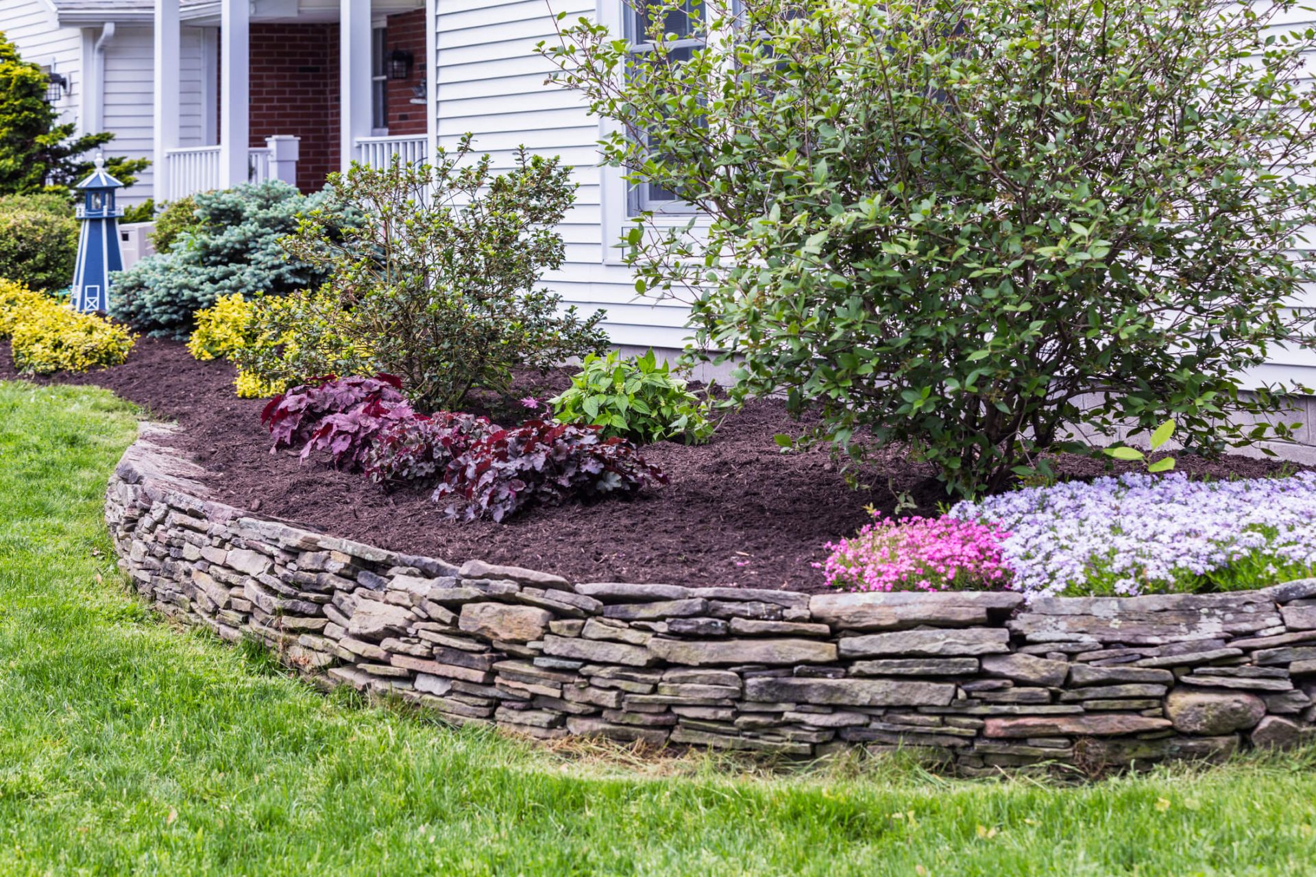 Mulch in a garden with a stone retaining wall.