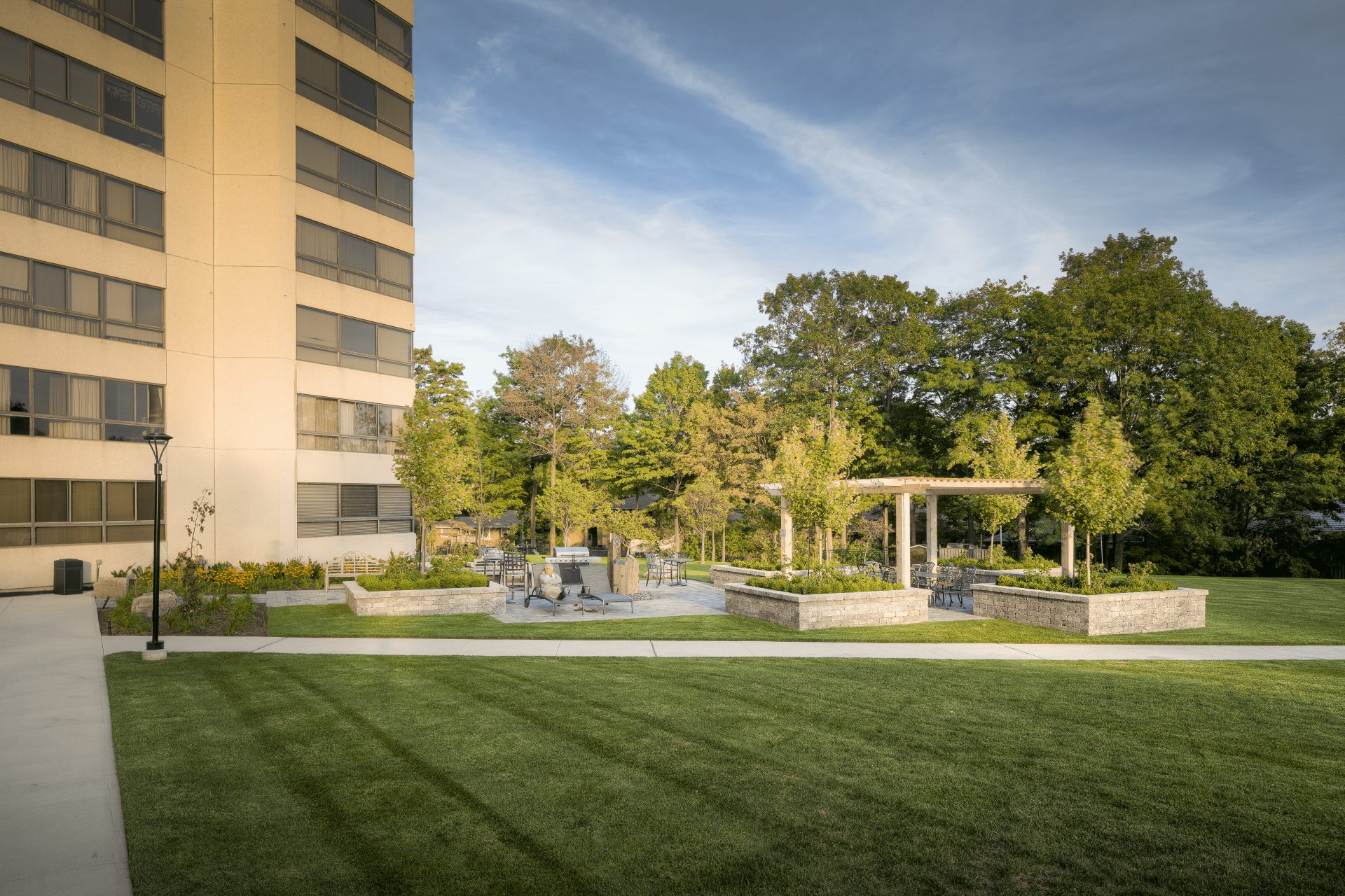An outdoor leisure area near a condo building with retaining wall gardens and freshly mowed grass.